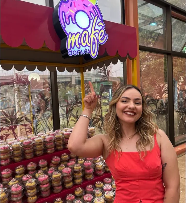 Proprietária da Mafê Donuts em frente à exposição da marca